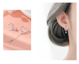 Detail of asymmetric S925 silver hoop earrings with white zircon on a female model