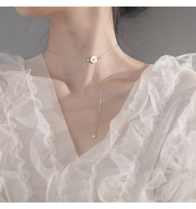 Detailed view of s925 silver daisy tassel necklace worn on a woman's collarbone