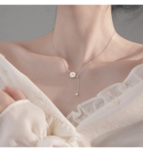 Close-up of 925 sterling silver daisy necklace with a tassel pendant on model neck