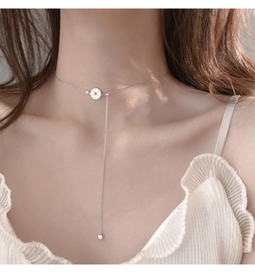 Macro view of 925 sterling silver daisy necklace with delicate tassel and white petal detail