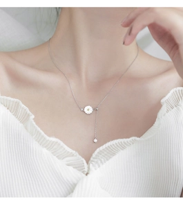 Close-up of 925 silver necklace featuring a daisy pendant and hanging tassel detail