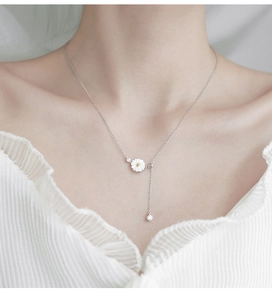 Close-up of S925 sterling silver daisy necklace with tassel on a female neck