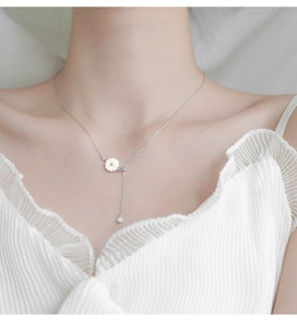 Detail of 925 sterling silver necklace with daisy pendant and zircon on a female model