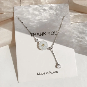 925 silver daisy necklace with tassel and shell details on a silk background