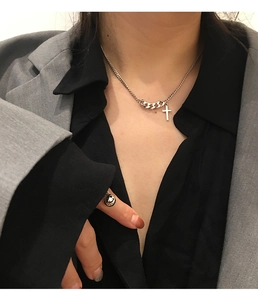 Detailed view of silver cross necklace and smiley face ring set on female model