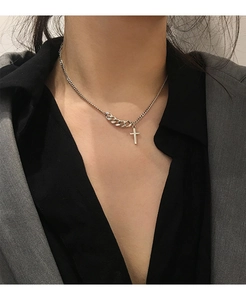 Close-up of vintage cross necklace with curb chain stitching on a gray blazer suit