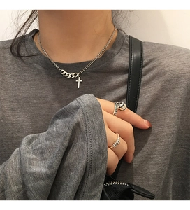 Detail of vintage 925 silver cross necklace and minimalist rings on female model