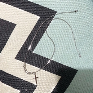 Detail of S925 sterling silver cross pendant with asymmetric cable and curb chain style