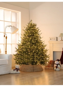 Albero di Natale con luci LED calde e base in rattan in un soggiorno accogliente