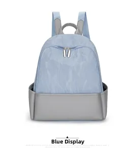 Detail of light blue nylon backpack showing crinkled texture and silver metal zippers