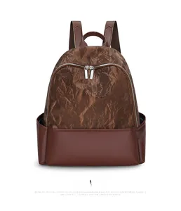 Detail of a brown two-tone backpack featuring pleated synthetic leather and silver zippers