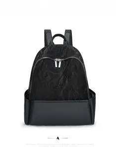 Front detail of black backpack showing contrast of wrinkled fabric and smooth leather texture