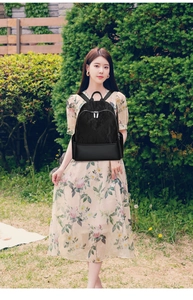 Outdoor shot of a woman wearing a black backpack with lace texture and silver zippers