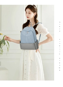 Detail view of a dual-tone nylon backpack in light blue and grey on a female model