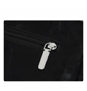 Detail of silver metal zipper and smooth slider on black textured leather backpack