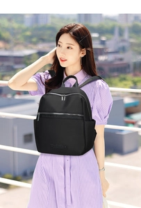 Outdoor view of a stylish black nylon backpack with silver zippers and side pockets