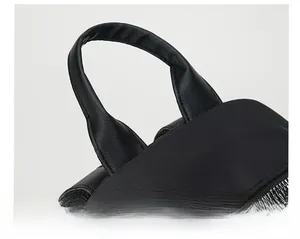 Detail of the reinforced leather handle and durable nylon fabric on black backpack