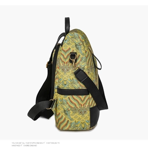 Side view of traditional yellow brocade backpack showing leather trim and metal hooks