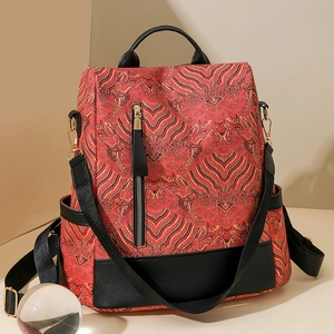 Detail view of red wave pattern jacquard backpack with black leather trim and metal buckles