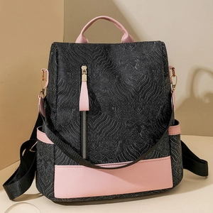 Close-up of black embossed texture and pink leather panels on a versatile backpack