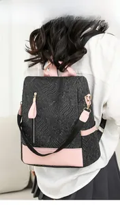 Detail of black embossed women's backpack with pink faux leather trim and woven straps