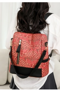 Close-up of red Chinese wave pattern backpack with black leather base and gold zipper