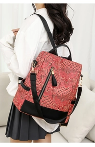 Detail of national style backpack featuring red gold patterns and black leather base