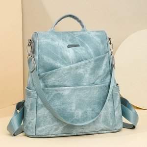 Detail eines blauen PU-Rucksacks mit Denim-Textur und Metall-Logo auf der Front