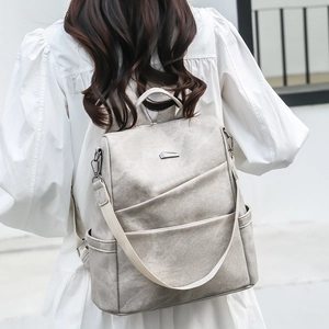 Nahaufnahme eines modischen hellgrauen PU-Lederrucksacks mit Kreuzfalten am Model