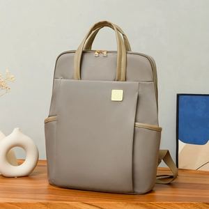 Détail d'un sac à dos en nylon gris avec poignées en cuir sur une table en bois