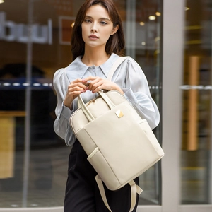 Détail d'un sac à dos d'ordinateur beige minimaliste avec logo métallique et fermetures
