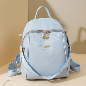 Detail of light blue Oxford backpack featuring gold zippers and front pocket texture