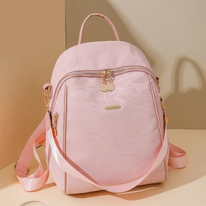 Detailed macro view of pink nylon backpack with gold-tone metal zippers and accents