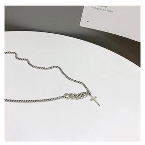 Detail of 925 silver necklace with asymmetric chain and cross pendant on a modern background