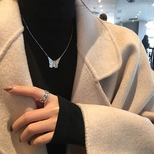 Detail of silver butterfly pendant necklace and hollow geometric ring on a model