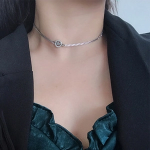Detail of silver smiley face pendant on a spiral chain worn with a dark blazer