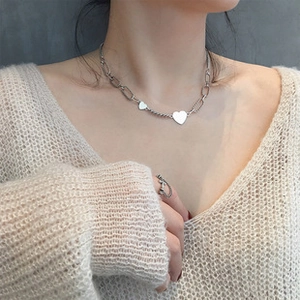 Detail of 925 sterling silver heart pendant necklace on model wearing beige knit sweater
