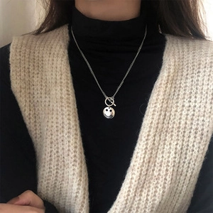 Silver necklace featuring a round smiley face pendant and OT toggle clasp on model