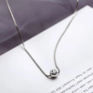 Detail of S925 silver snake chain necklace featuring a minimalist smiley face sphere pendant