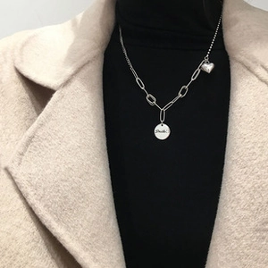 Detail of silver heart and Smile coin pendant on a stylish vintage multi-link bracelet