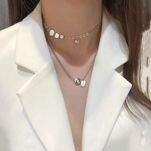Close-up of double layered S925 silver necklace with heart and bead pendants on model