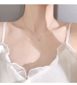 Detail view of a silver planet pendant necklace worn by a model on the collarbone