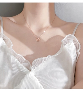 Close-up of rose gold planet pendant necklace with zircon inlay on female model
