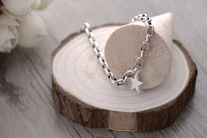 Detail of S925 sterling silver chunky link chain bracelet with a hollow star charm on wood