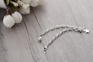 Detail shot of a minimalist S925 silver star bracelet with lobster clasp on wood