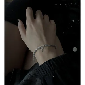 Dettaglio del bracciale a doppio strato in argento s925 con croce sul polso della modella