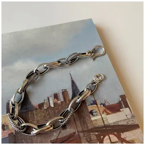 Vintage chunky silver chain bracelet with textured links and S-hook clasp on art book