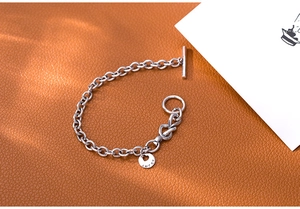Macro detail of silver OT buckle and round charm with Lucky engraving on leather