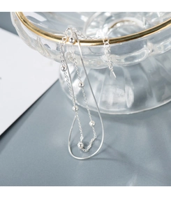 Detail of silver double-layer snake chain bracelet with beads on glass bowl edge