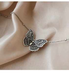 Detail eines Vintage-Schmetterlingsanhängers aus 925er Silber auf Seidenstoff